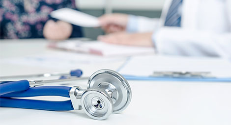 Stethoscope placed on doctors desk as they talk with a patient